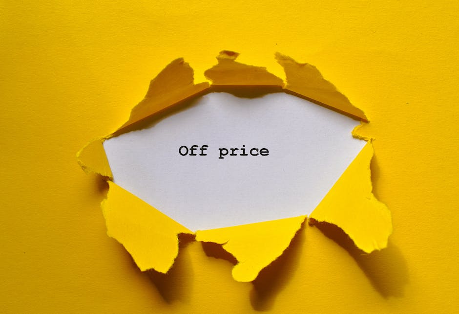 A bright yellow background paper has been torn open in the shape of an irregular circle, revealing a white rectangular sign underneath. The torn edges of the yellow paper curl outward, creating a laye